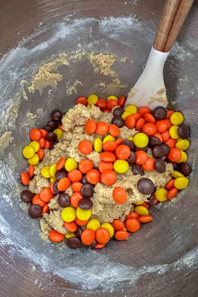 A mixing bowl filled with cookie dough and candies.
