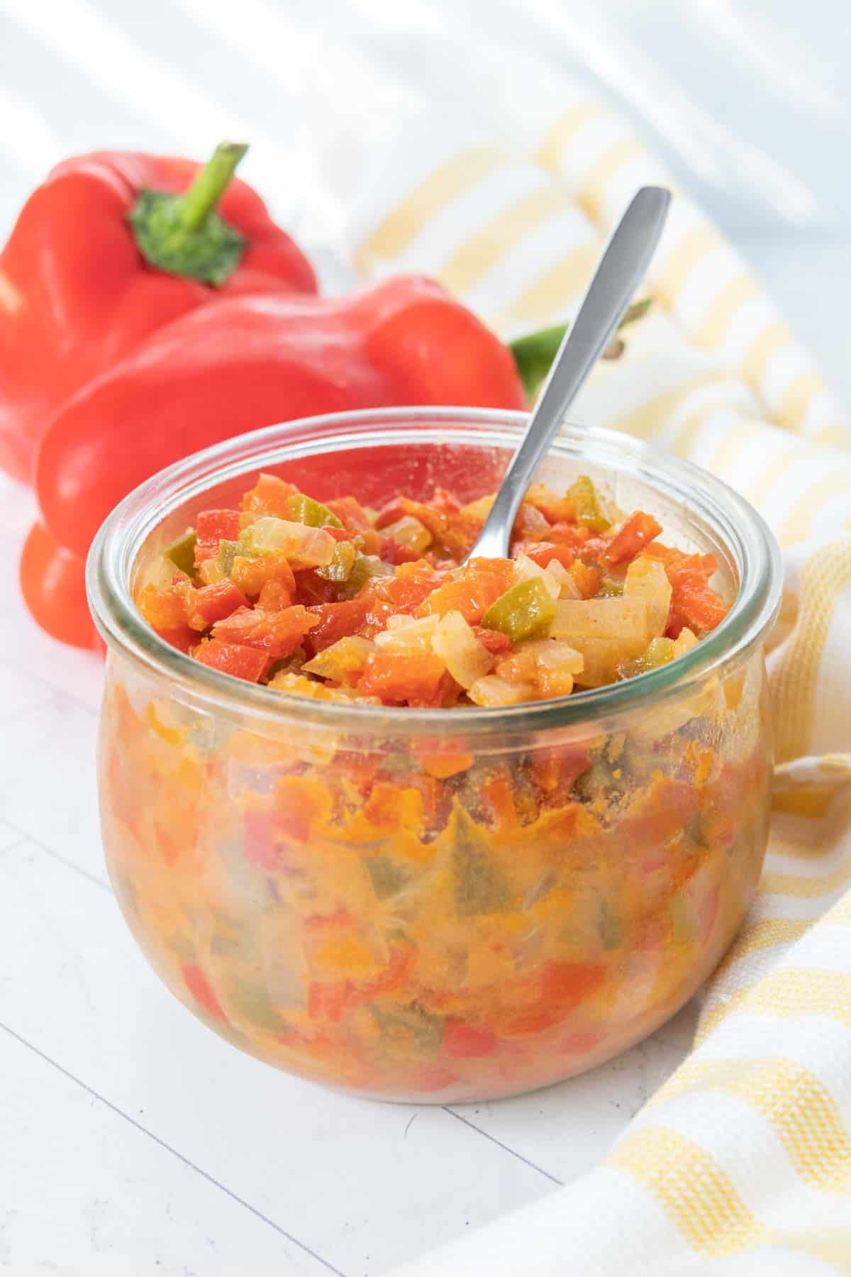 A bowl of vegetables with a spoon on a wooden table.