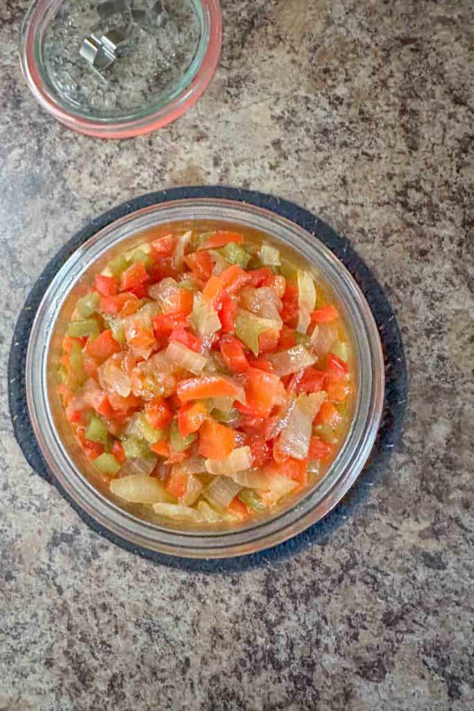 A bowl of relish in a glass on a counter.