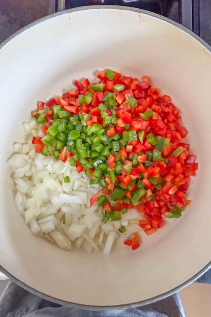 Onions and peppers in a pan on a stove.