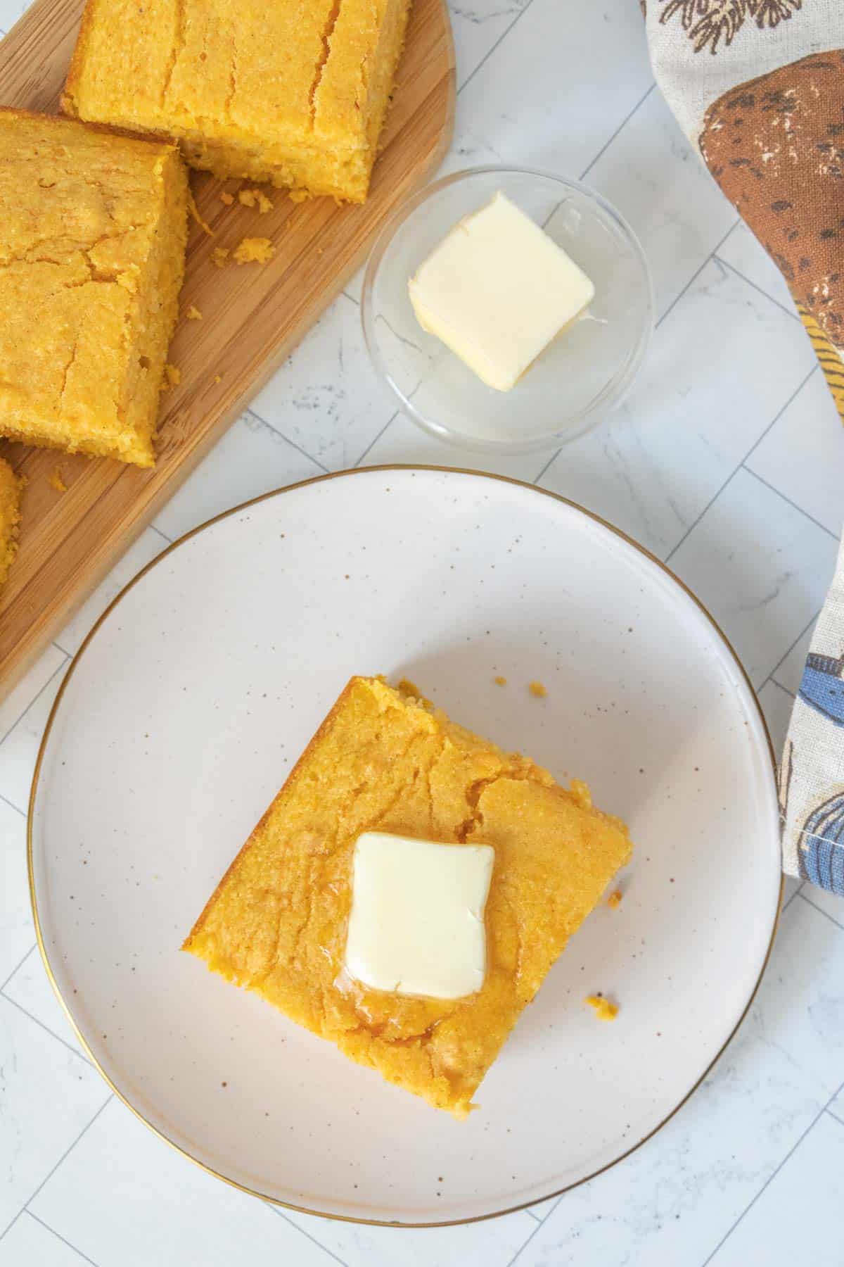 Cornbread with butter on a plate.