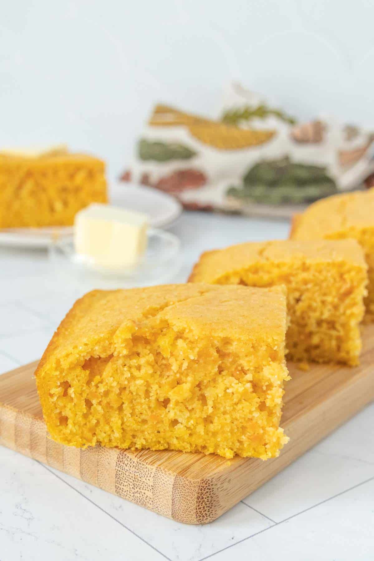 A slice of cornbread on a cutting board.