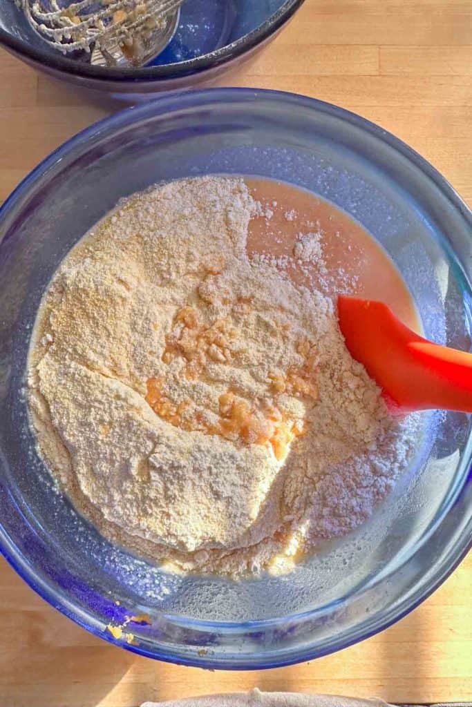 A bowl filled with flour and a red spatula.
