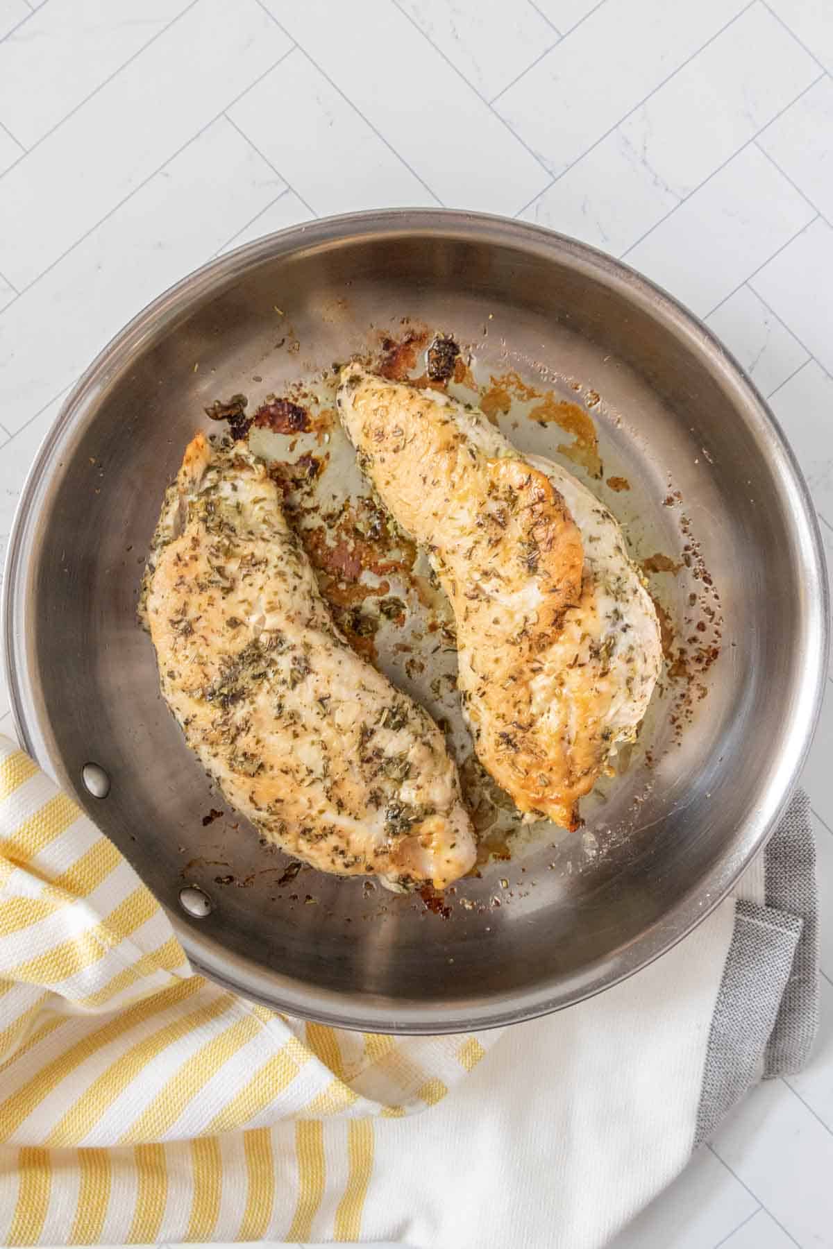 Turkey tenderloins in a skillet on a white tablecloth.