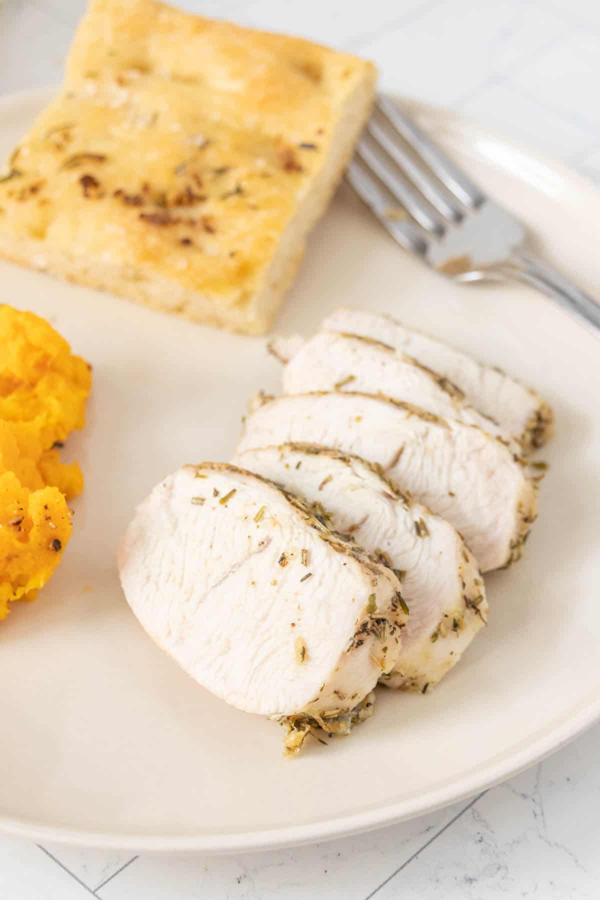 A plate with a slices of turkey and mashed potatoes.