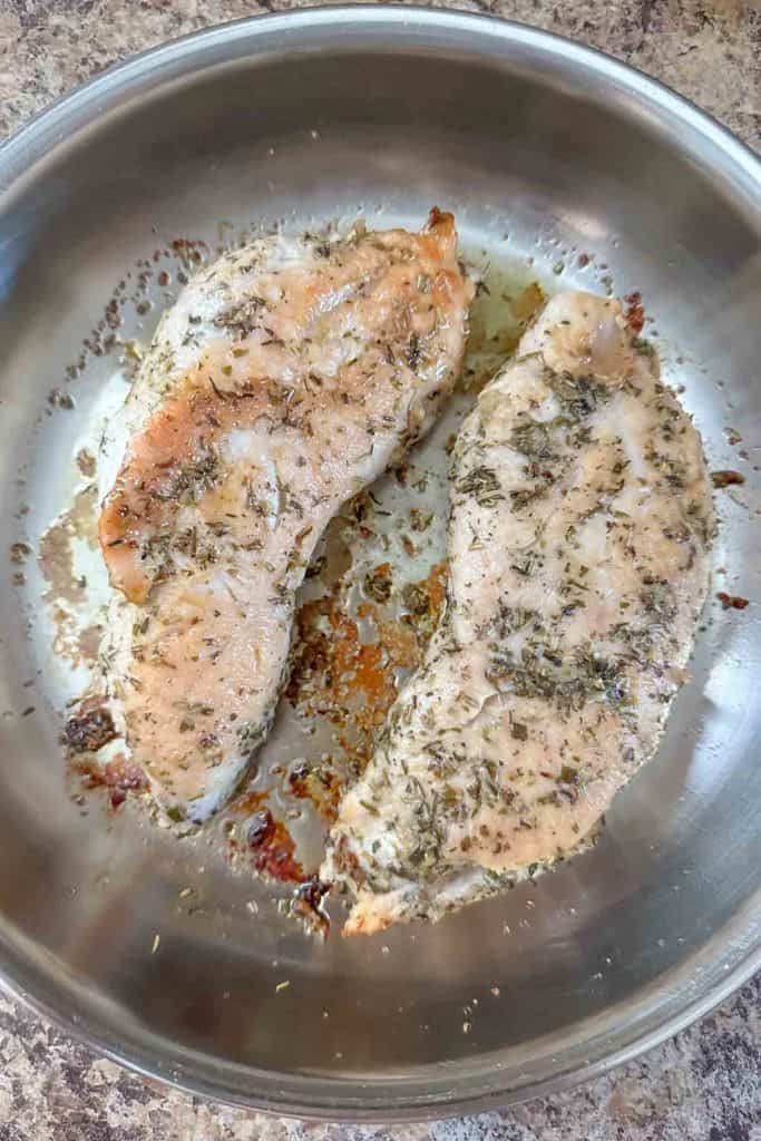 Two turkey tenderloins are being cooked in a pan.