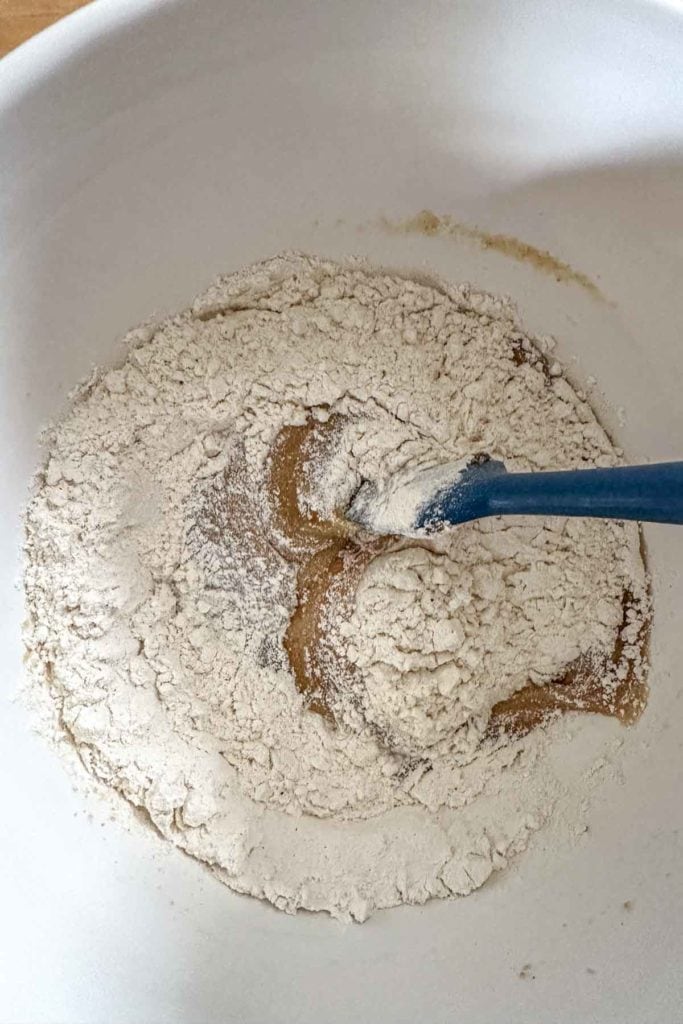 A bowl of flour with a blue spoon in it.