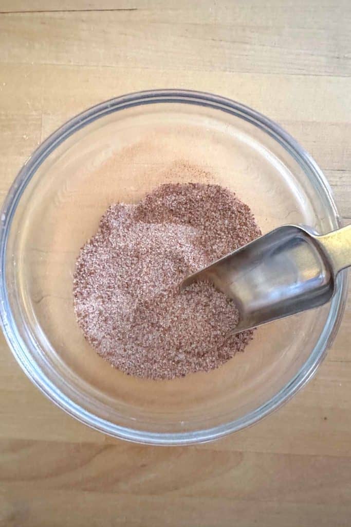 Cinnamon sugar in a glass bowl with a spoon.