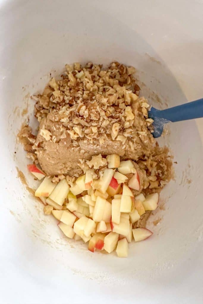 A bowl full of apples and nuts in a white bowl.