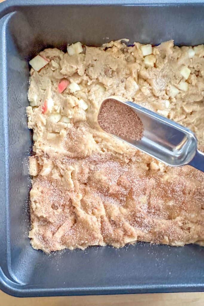 An apple cake in a baking pan with a spatula.