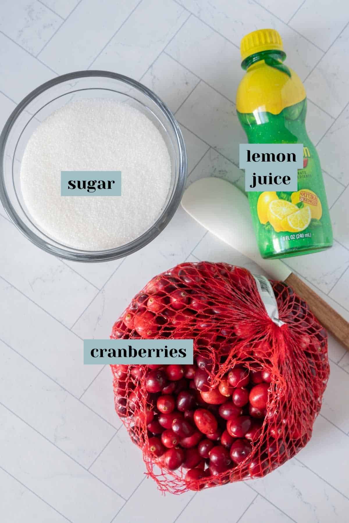 Cranberries, sugar, lemon juice, and sugar on a counter.