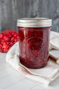 A jar of cranberry jam on a towel.