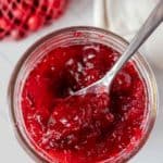 A bowl of cranberry sauce with a spoon.