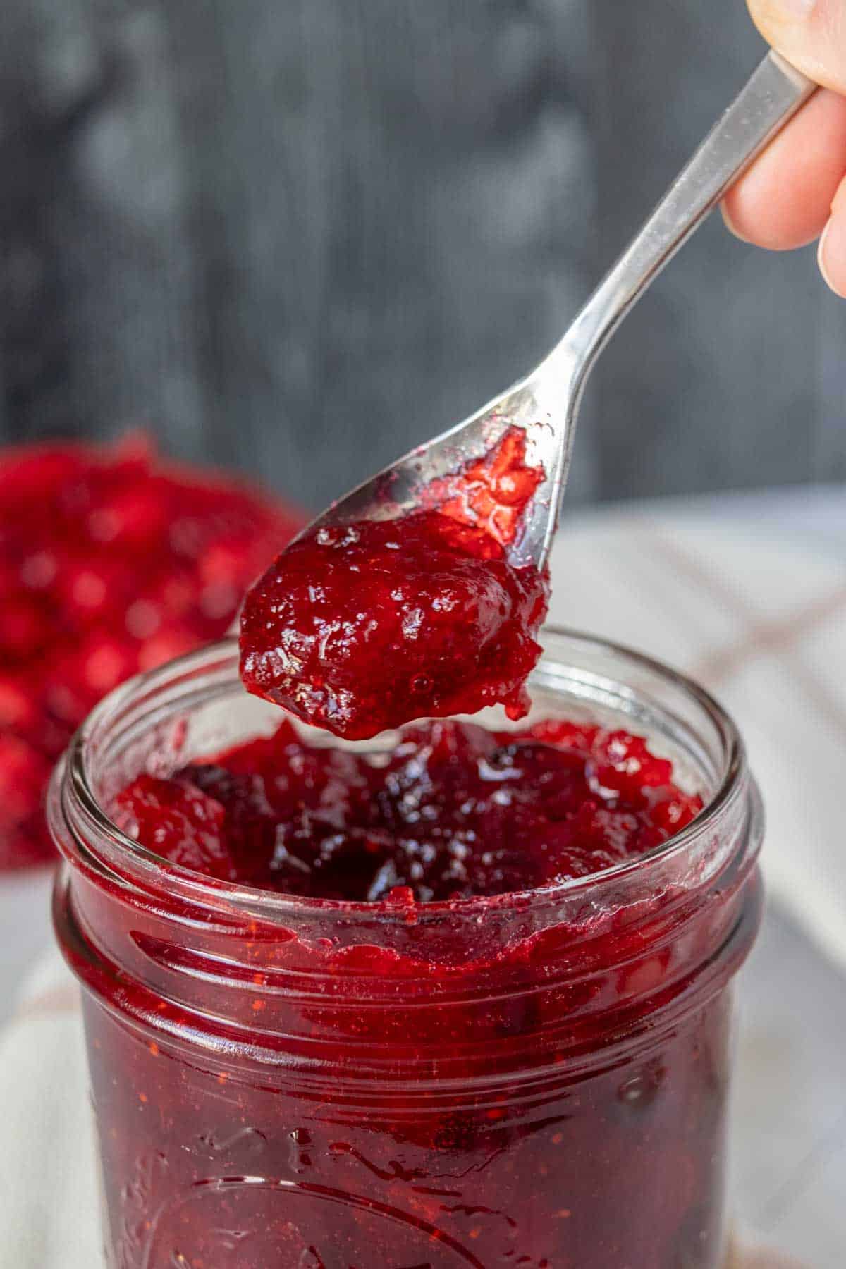 A spoonful of cranberry jam in a jar.