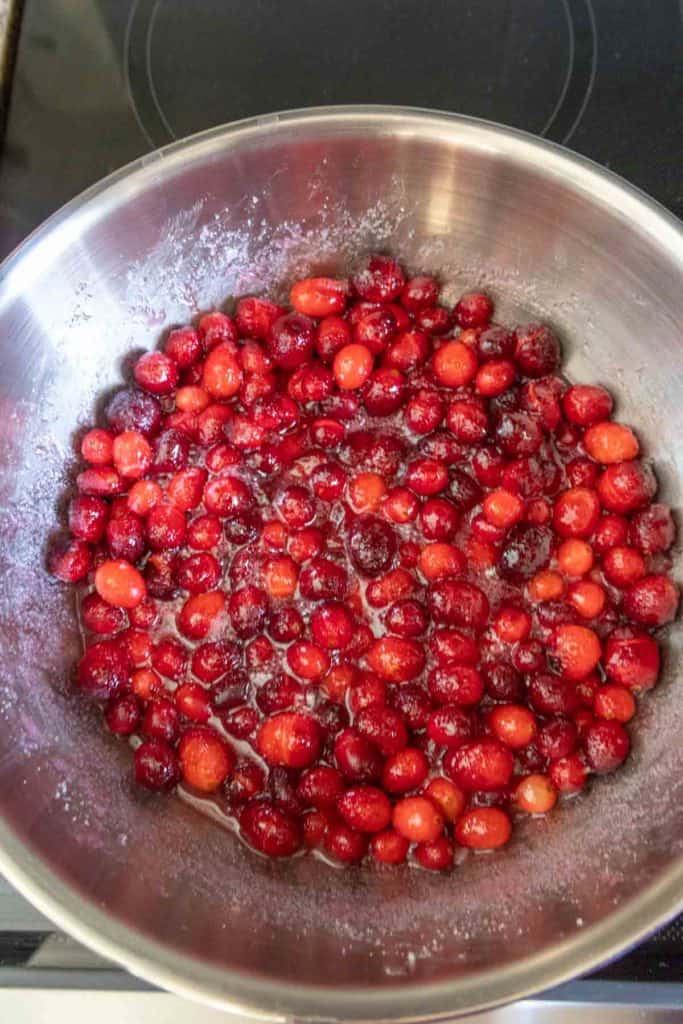 Cranberries being cooked in a pan on a stove.