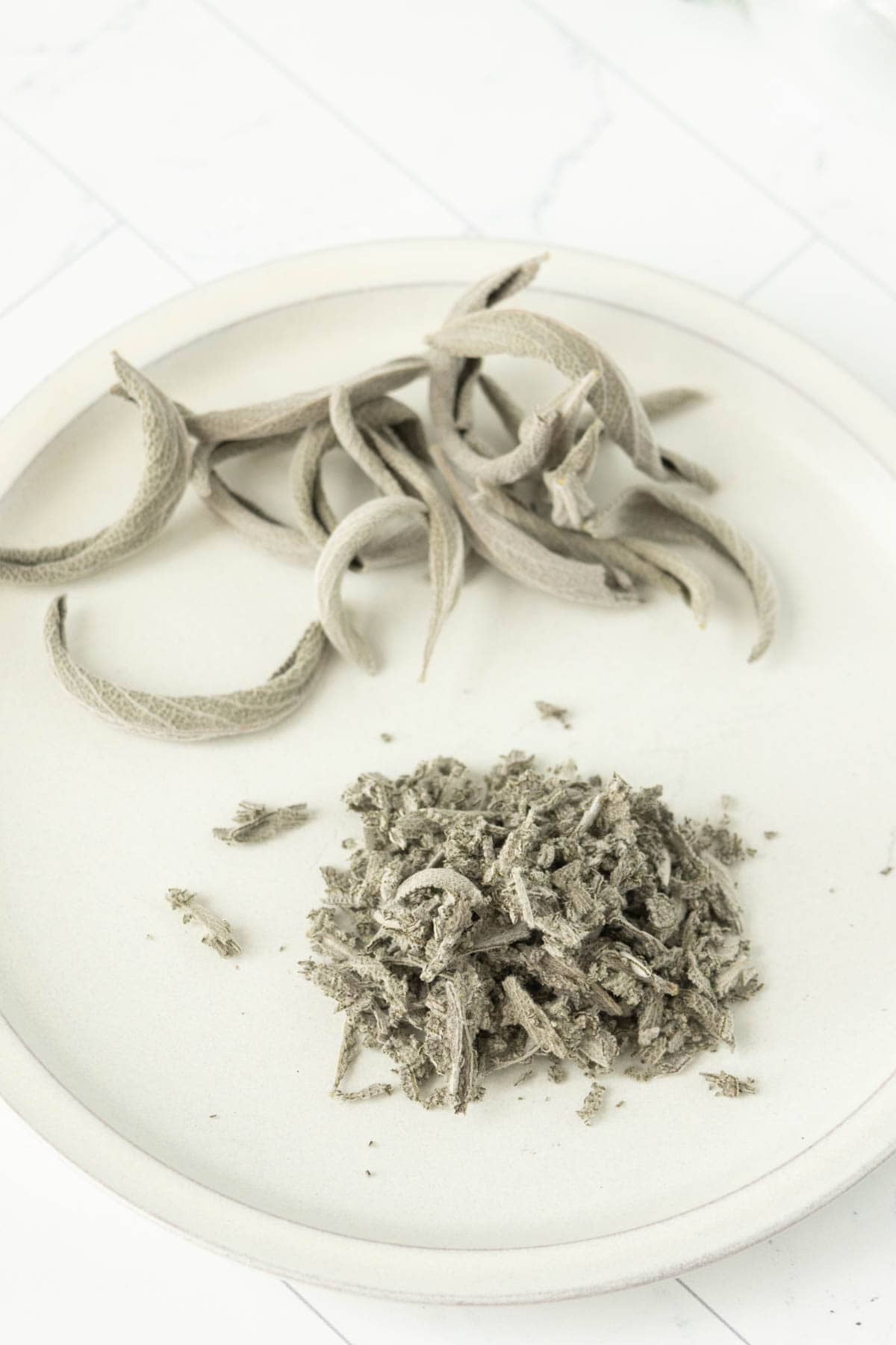 Dried sage leaves on a white plate.