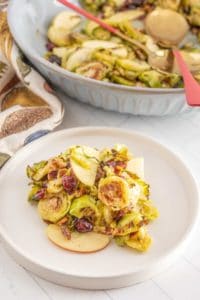 Brussel sprouts with apples and cranberries on a plate.