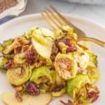 Brussels sprouts with apples and cranberries on a plate.