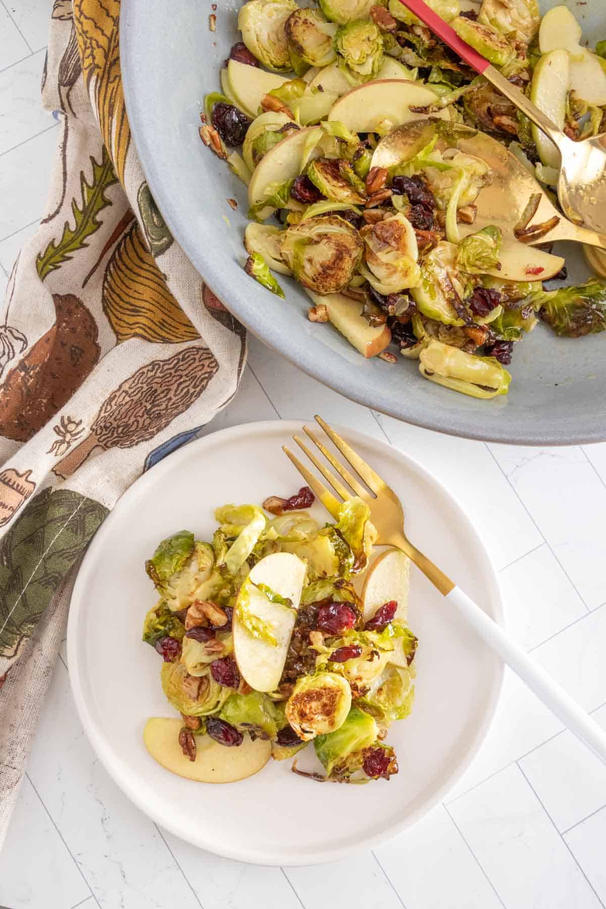 A plate of brussels sprouts with apples and cranberries.