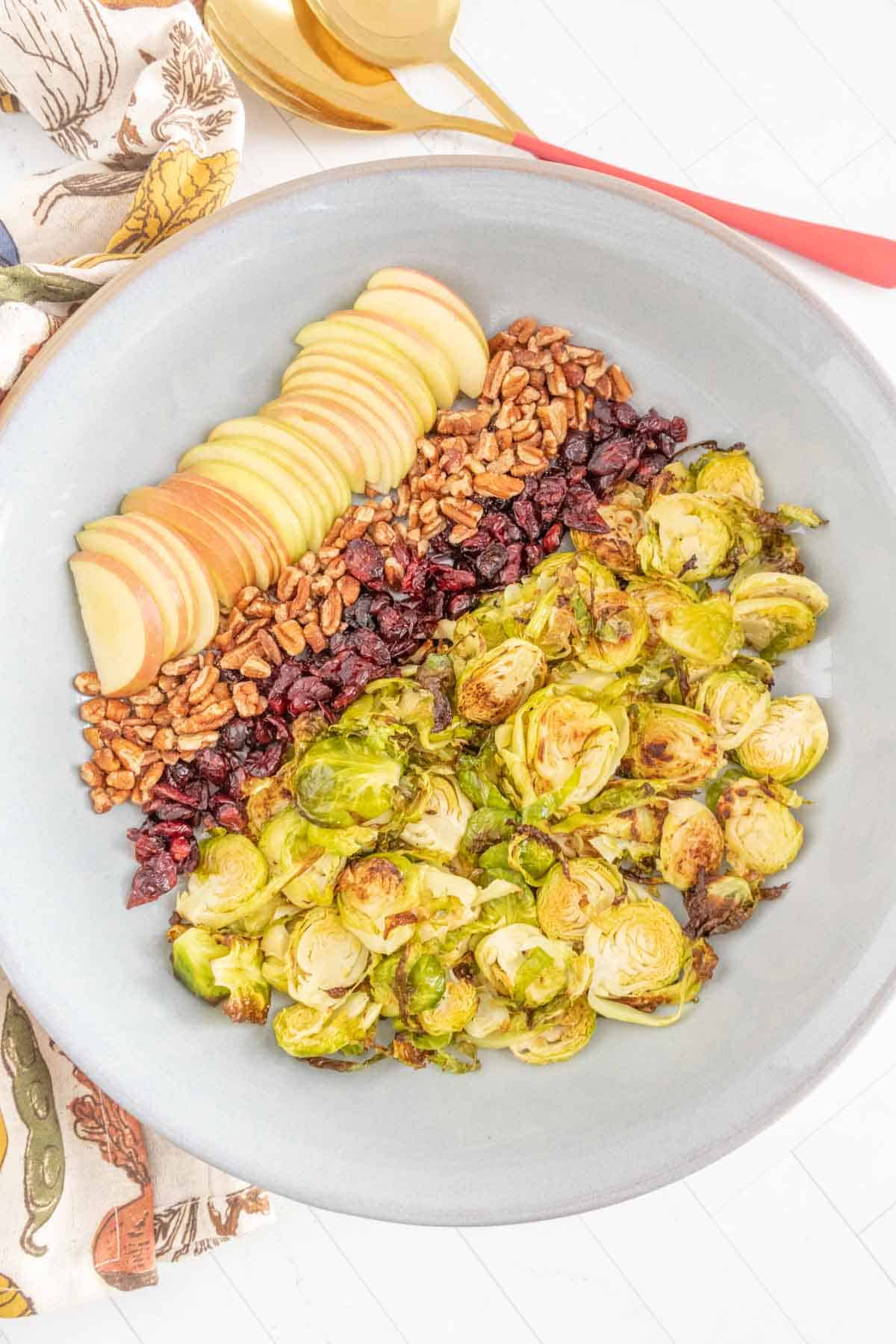 A bowl of brussels sprouts, apples and nuts.