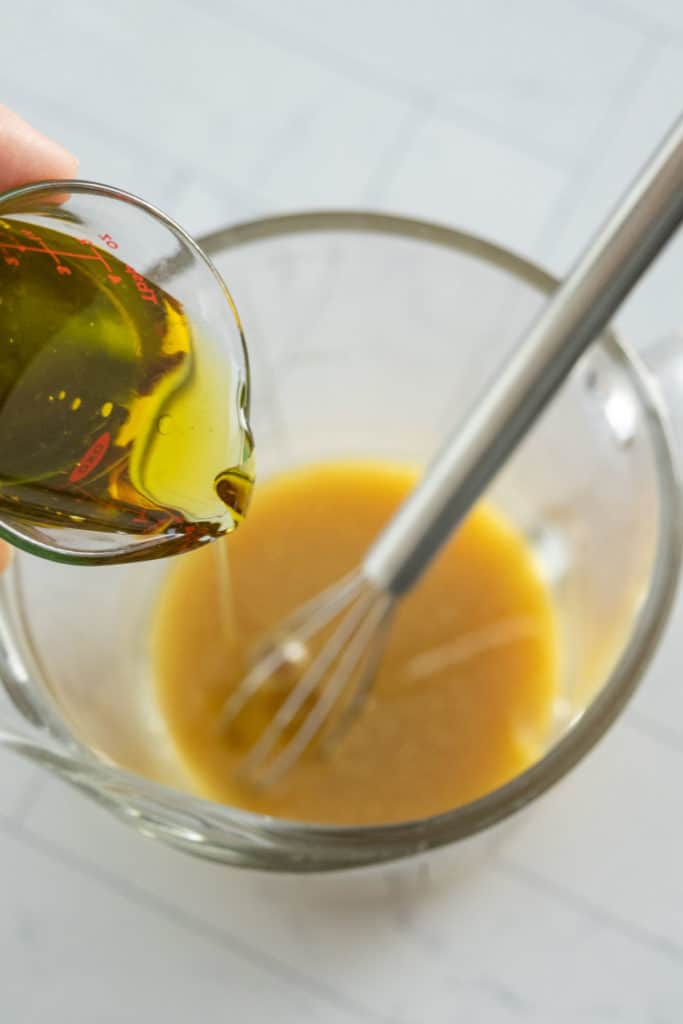 A person pouring oil into a glass bowl.