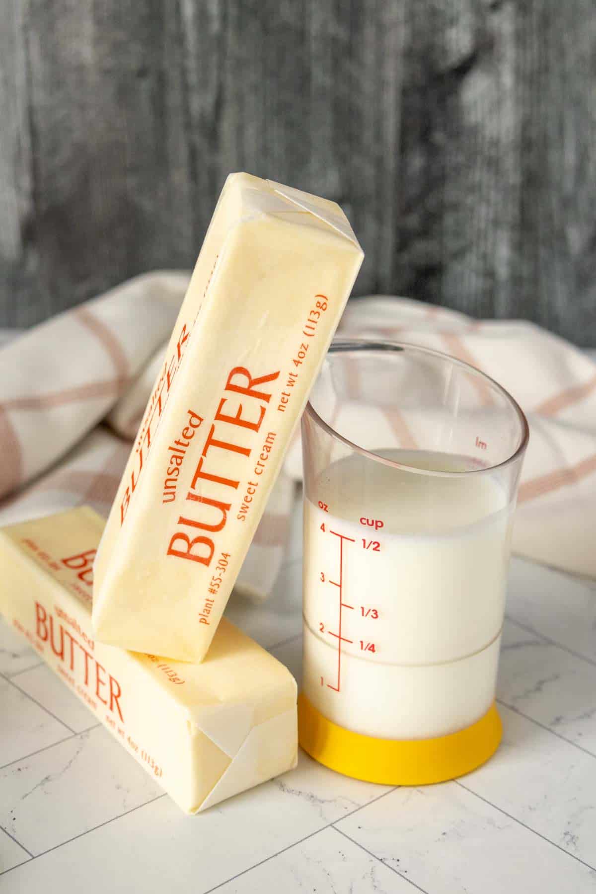 Butter on a table next to a measuring cup.