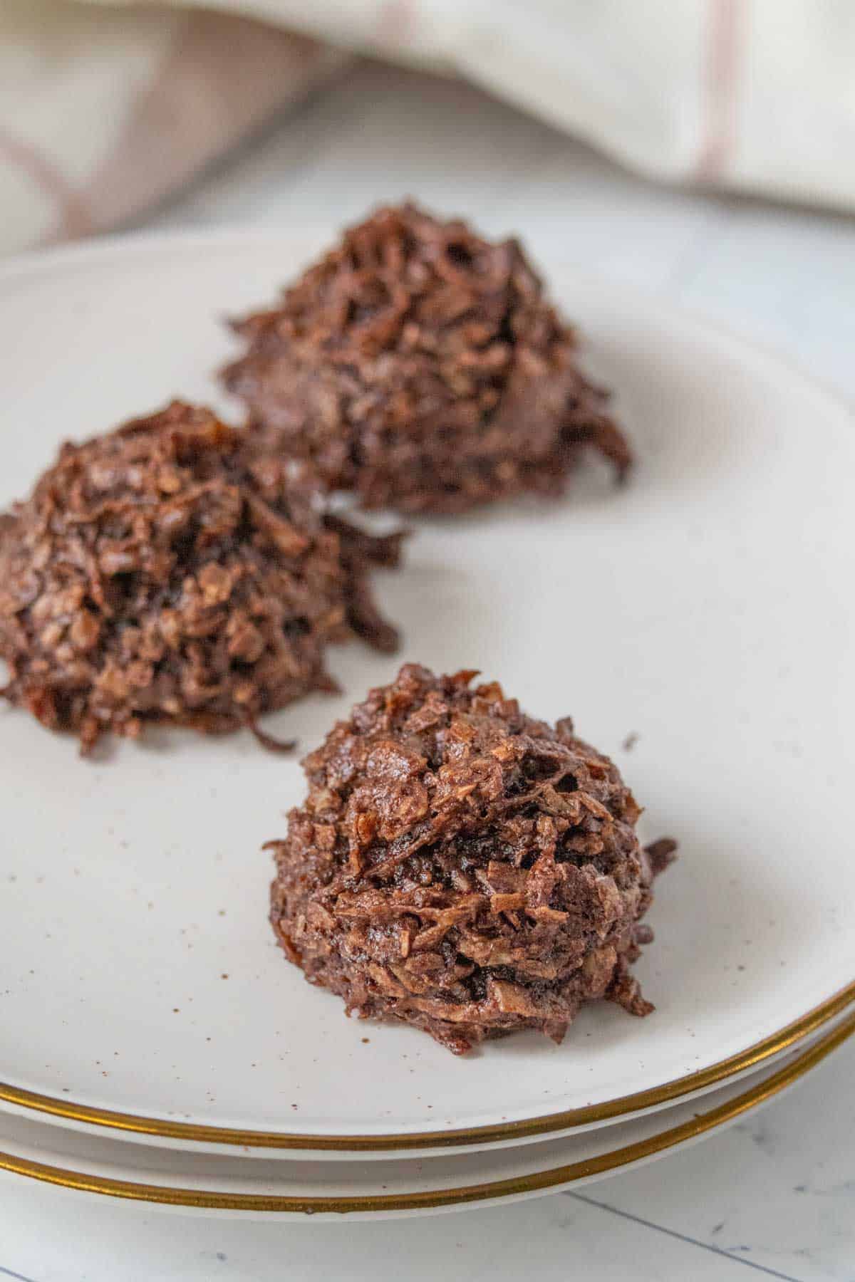 Three chocolate macaroons on a plate.