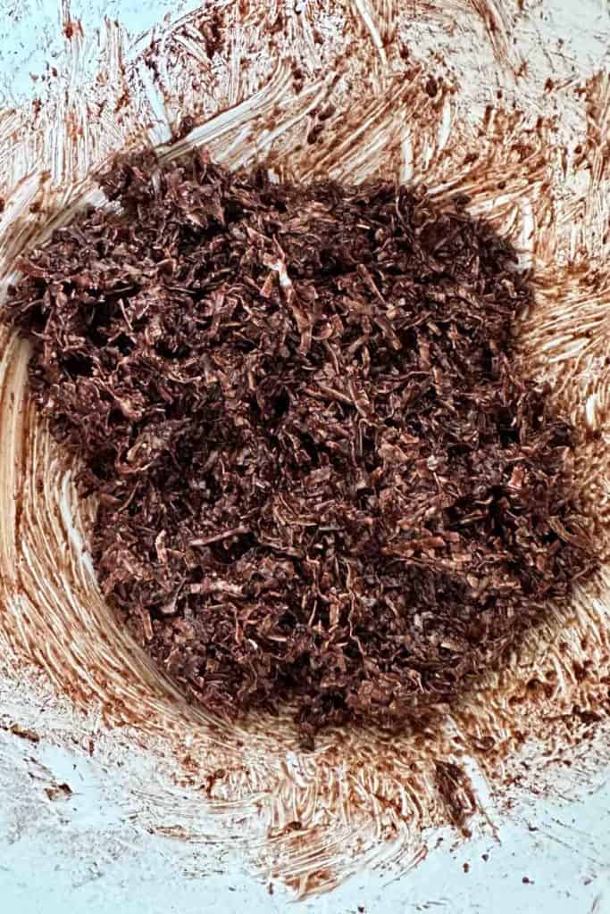 A bowl full of chocolate and coconut in a white bowl.