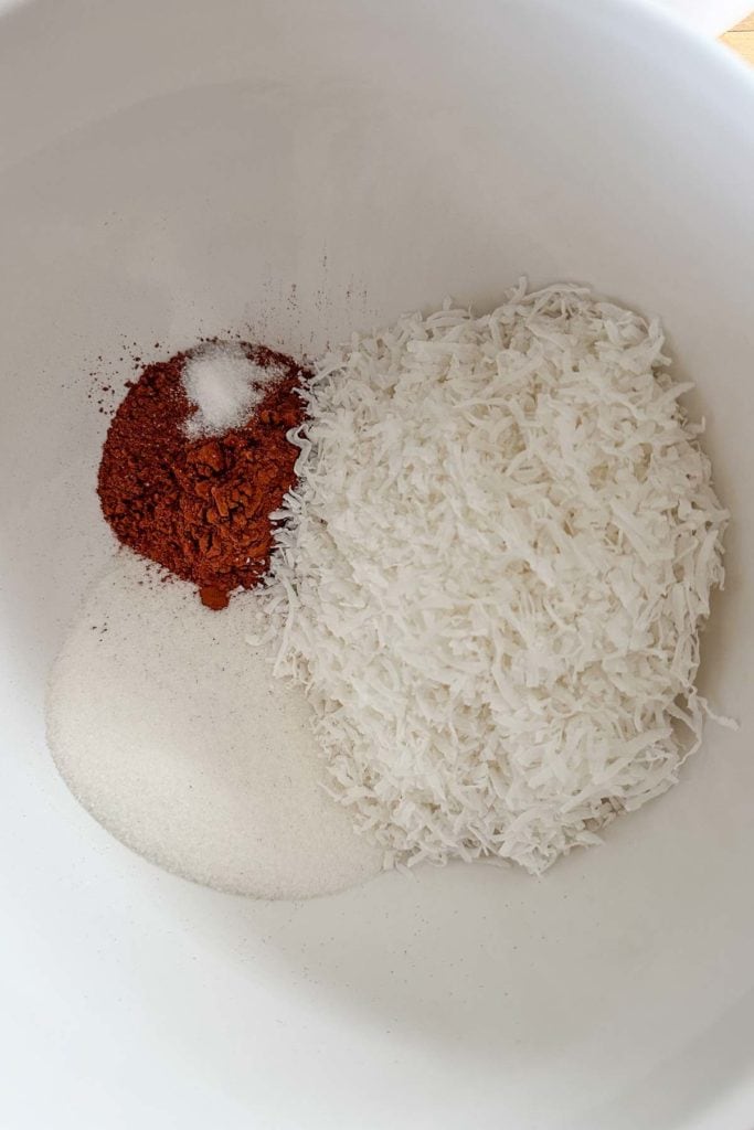 A bowl of coconut and sugar in a white bowl.