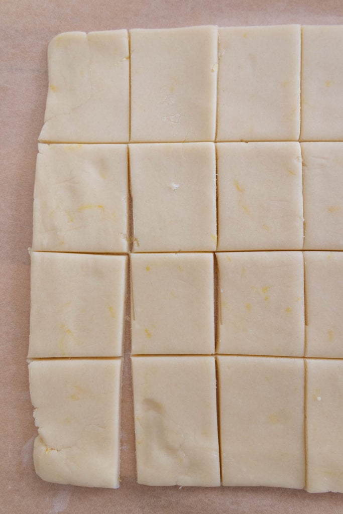 A piece of dough is cut into squares on a baking sheet.