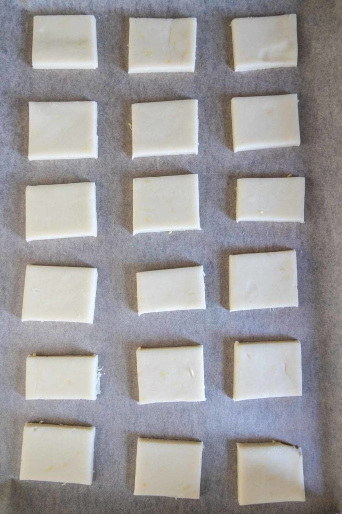 A baking sheet lined with squares of unbaked shortbread.