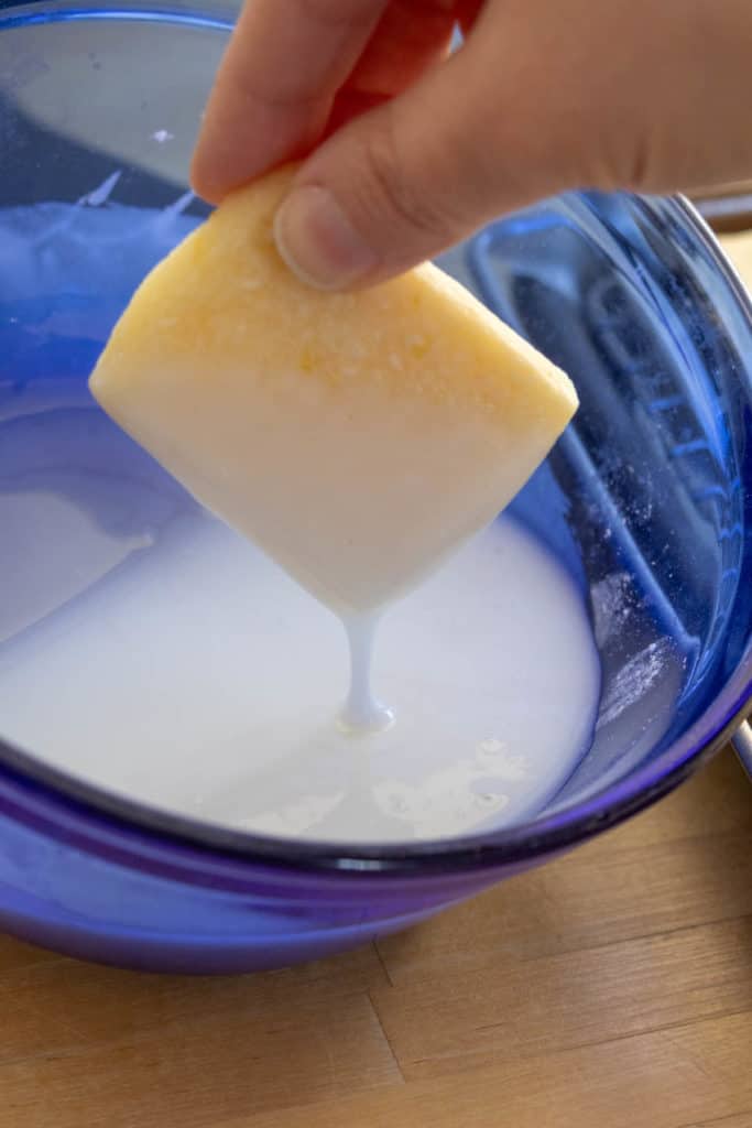 A person dipping a cookie into icing.