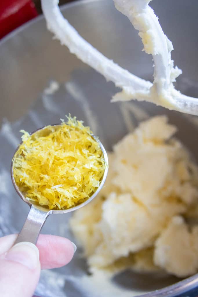 A person mixing a spoonful of lemon zest in a bowl.
