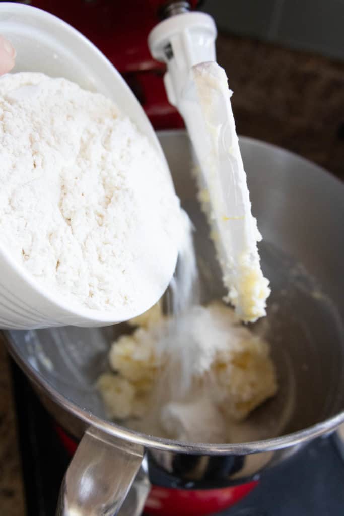 A person pouring flour into a mixing bowl.