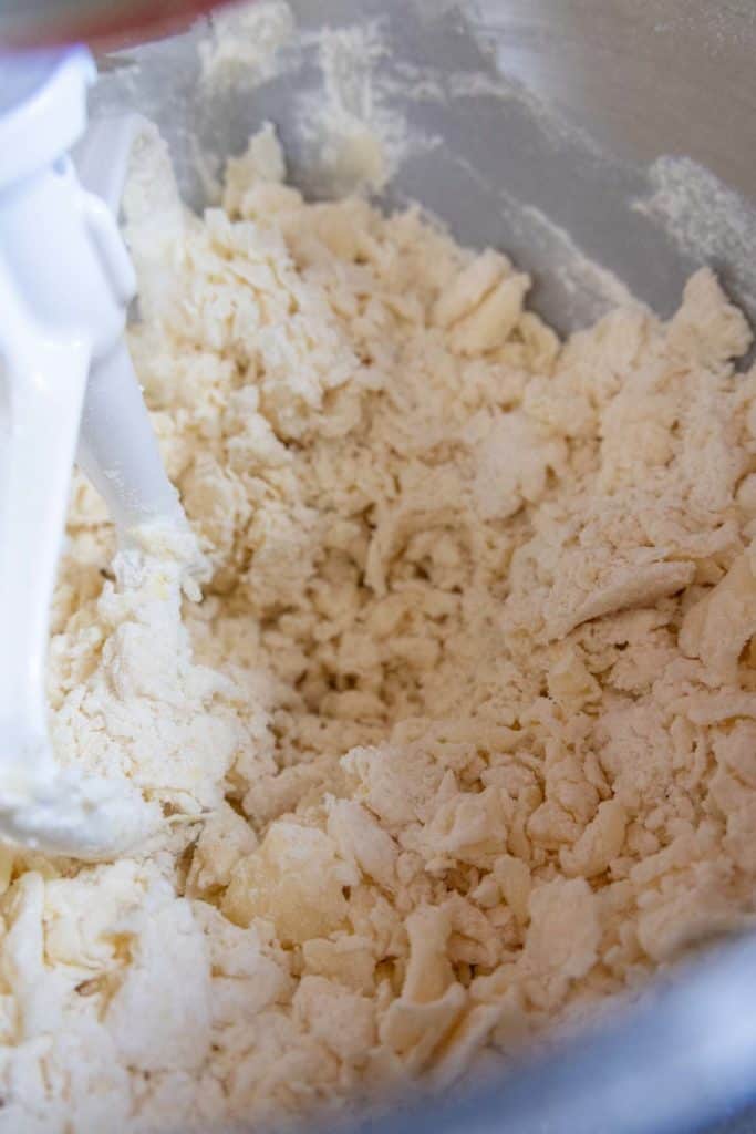 A bowl of dough being mixed with a mixer.