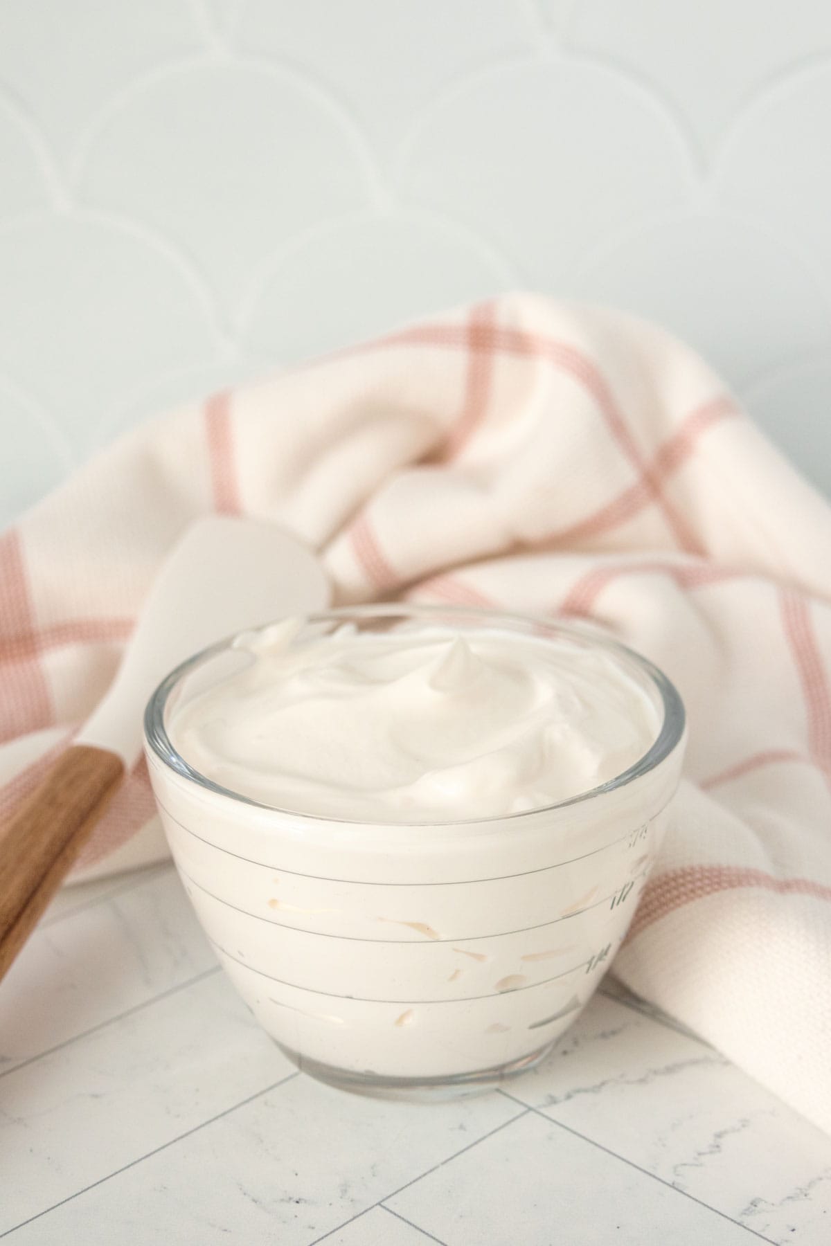 A bowl of sour cream with a wooden spoon next to it.