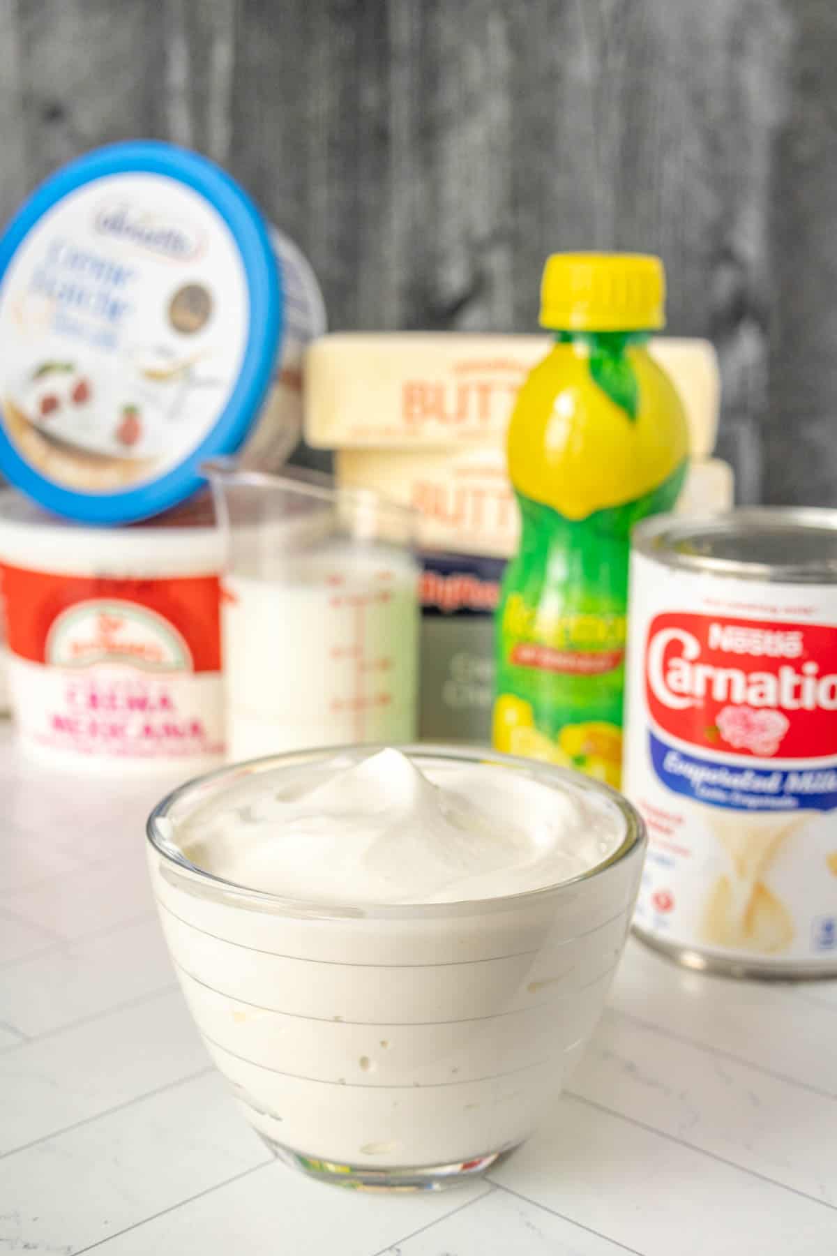 A bowl of sour cream and other ingredients on a table.