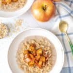 Two bowls of oatmeal with apples and oats.