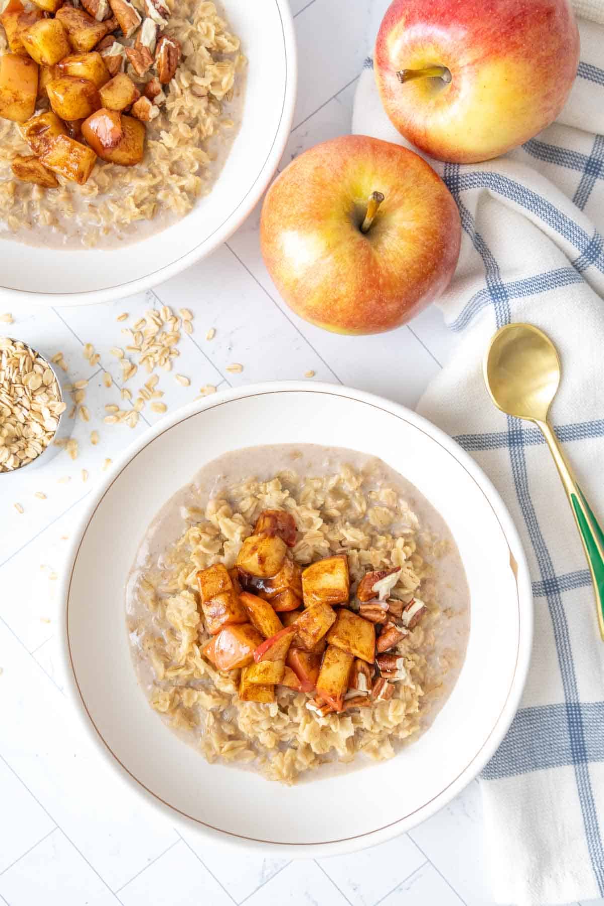 Two bowls of oatmeal with apples and oats.