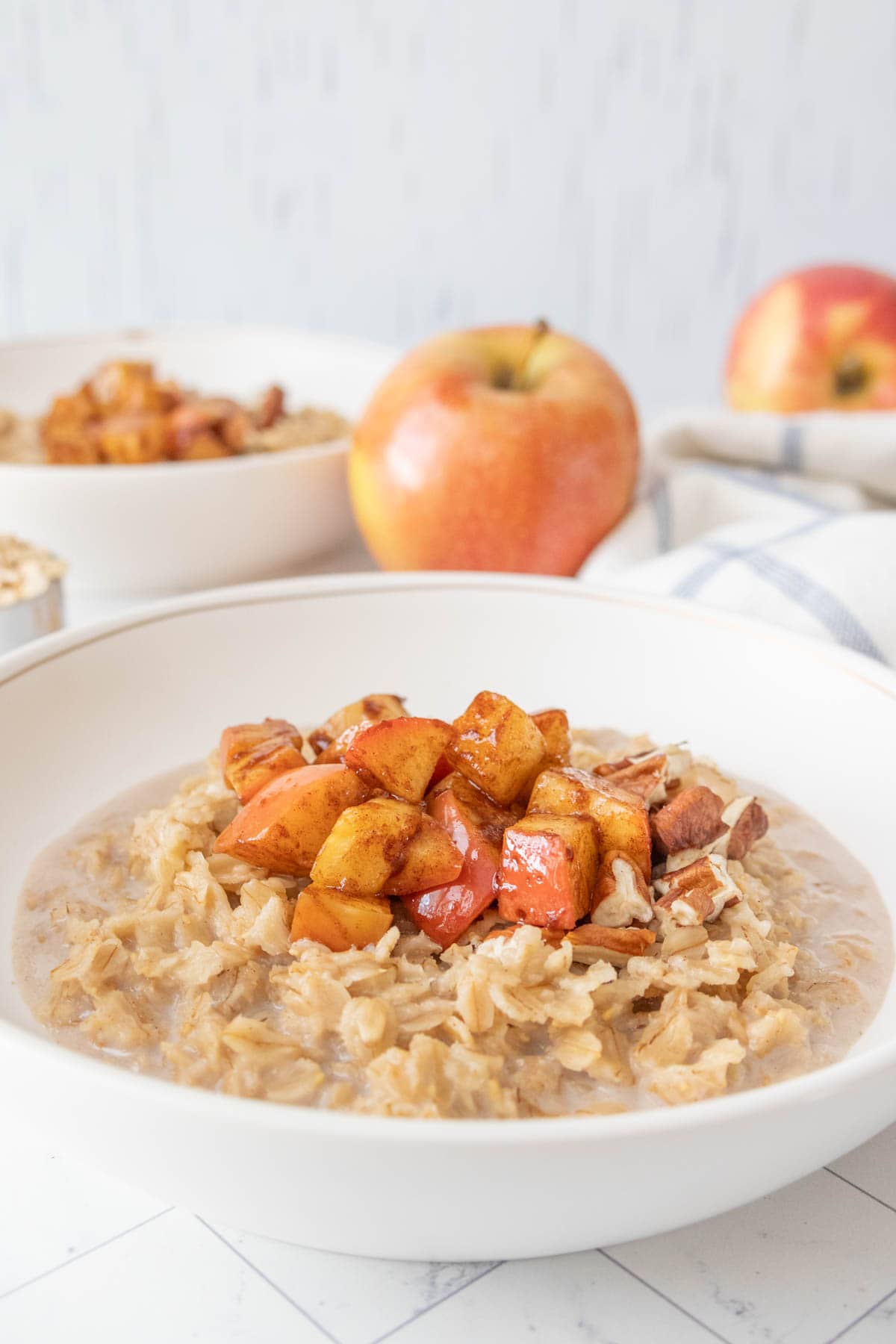A bowl of oatmeal with apples and nuts.