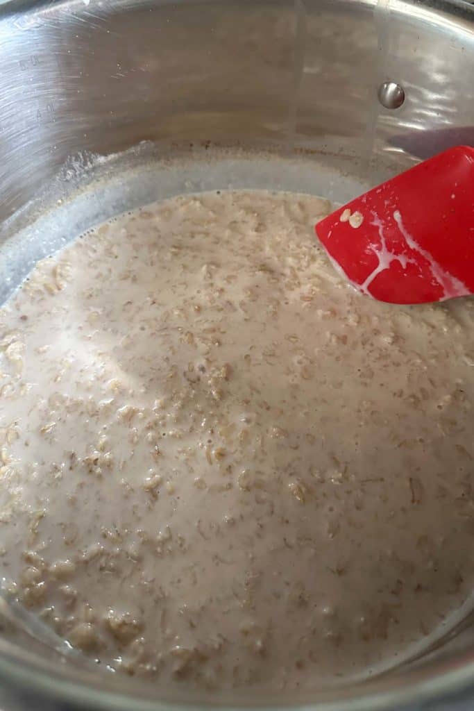 Oatmeal in a pot with a red spatula.