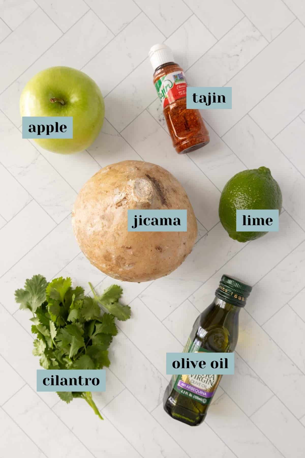 The ingredients for a jicama salad are laid out on a marble countertop.