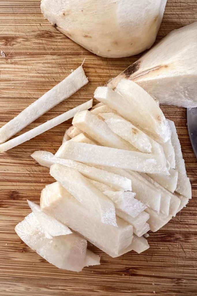 Sliced jicama on a cutting board with a knife.