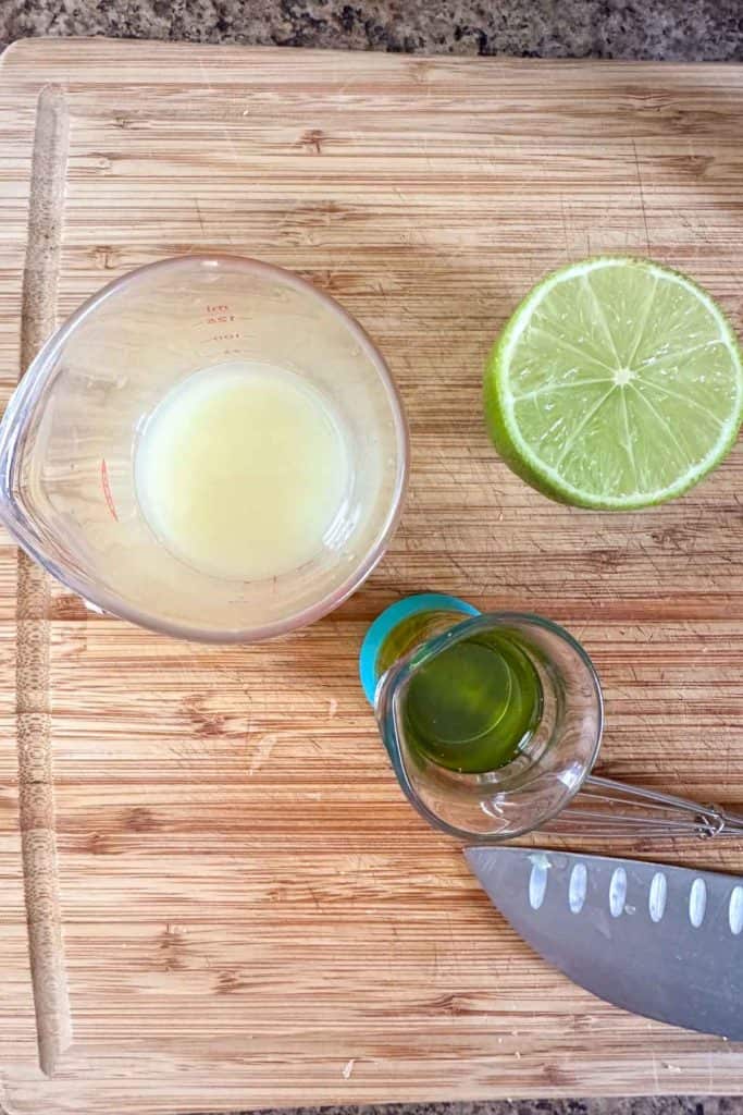 A cutting board with limes, lime juice, and a knife.
