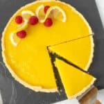 A lemon tart with a slice taken out of it.