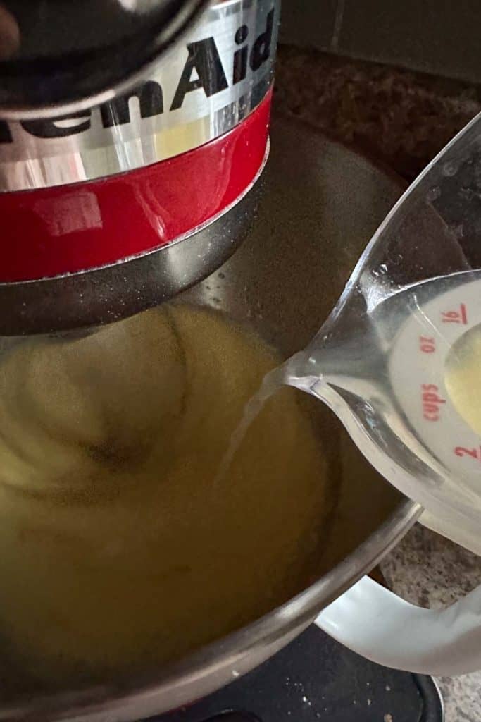 A bowl of liquid being poured into a mixer.