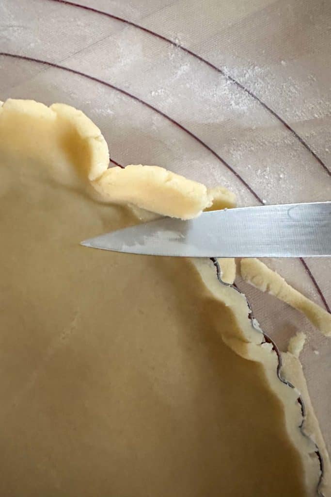 A knife is being used to cut a pie crust.