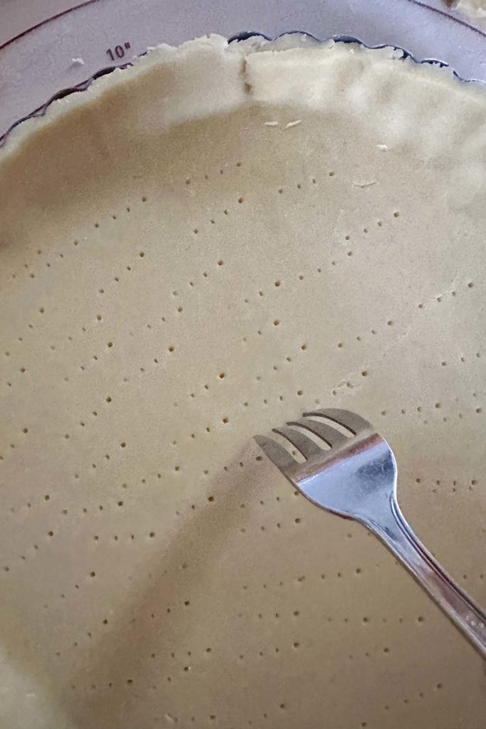 A person using a fork to cut a pie crust.