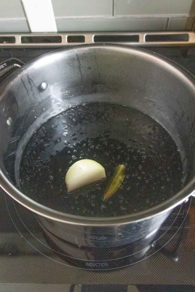 A pot filled with black liquid and a slice of onion.