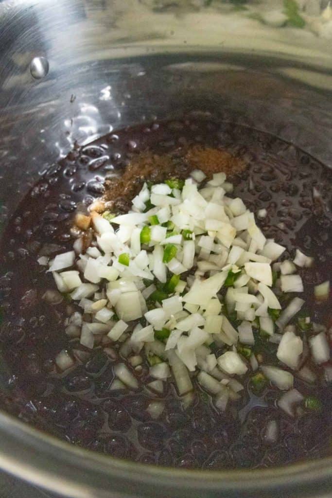 A bowl with black beans and onions in it.